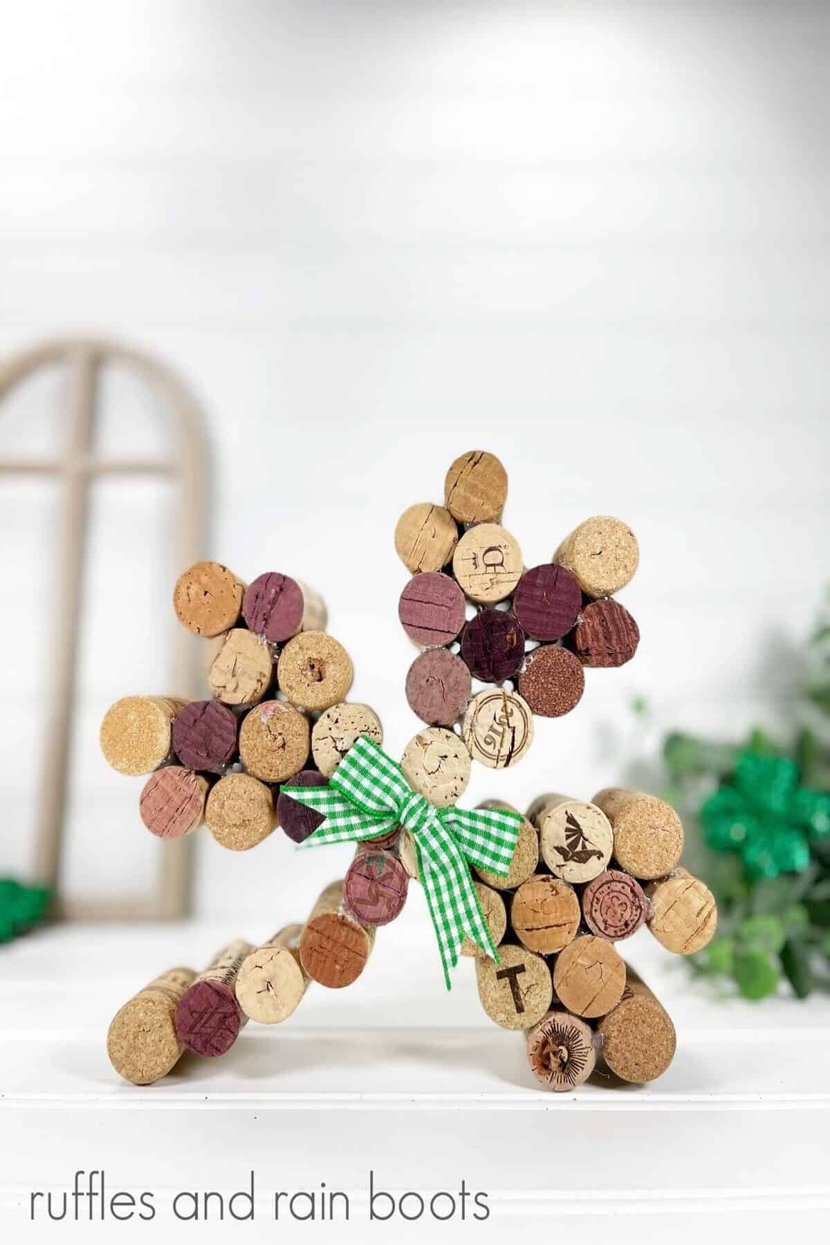 Close up photo of unpainted wine cork shamrock with a window cut out and shamrock decorations in the background.