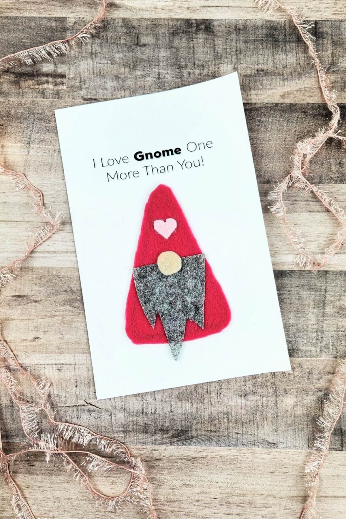 Easy Gnome Valentine's Day Card on a weathered wood surface surrounded by a fringe trim.
