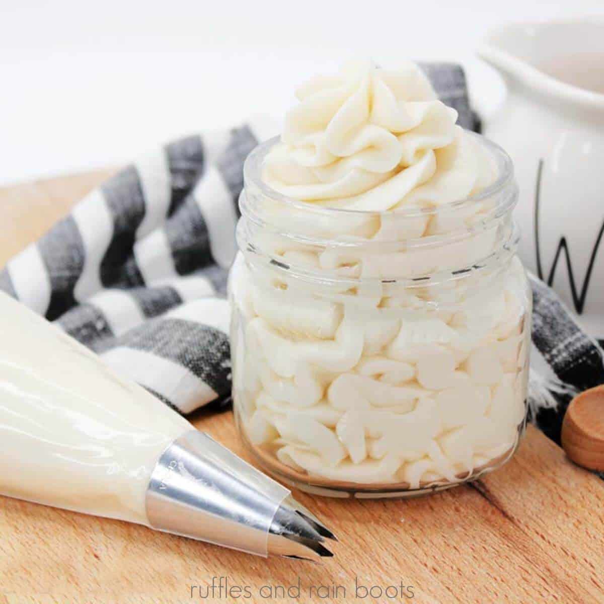 Easy buttercream frosting recipe piped into a mini mason jar next to piping bag with star tip and kitchen towel.