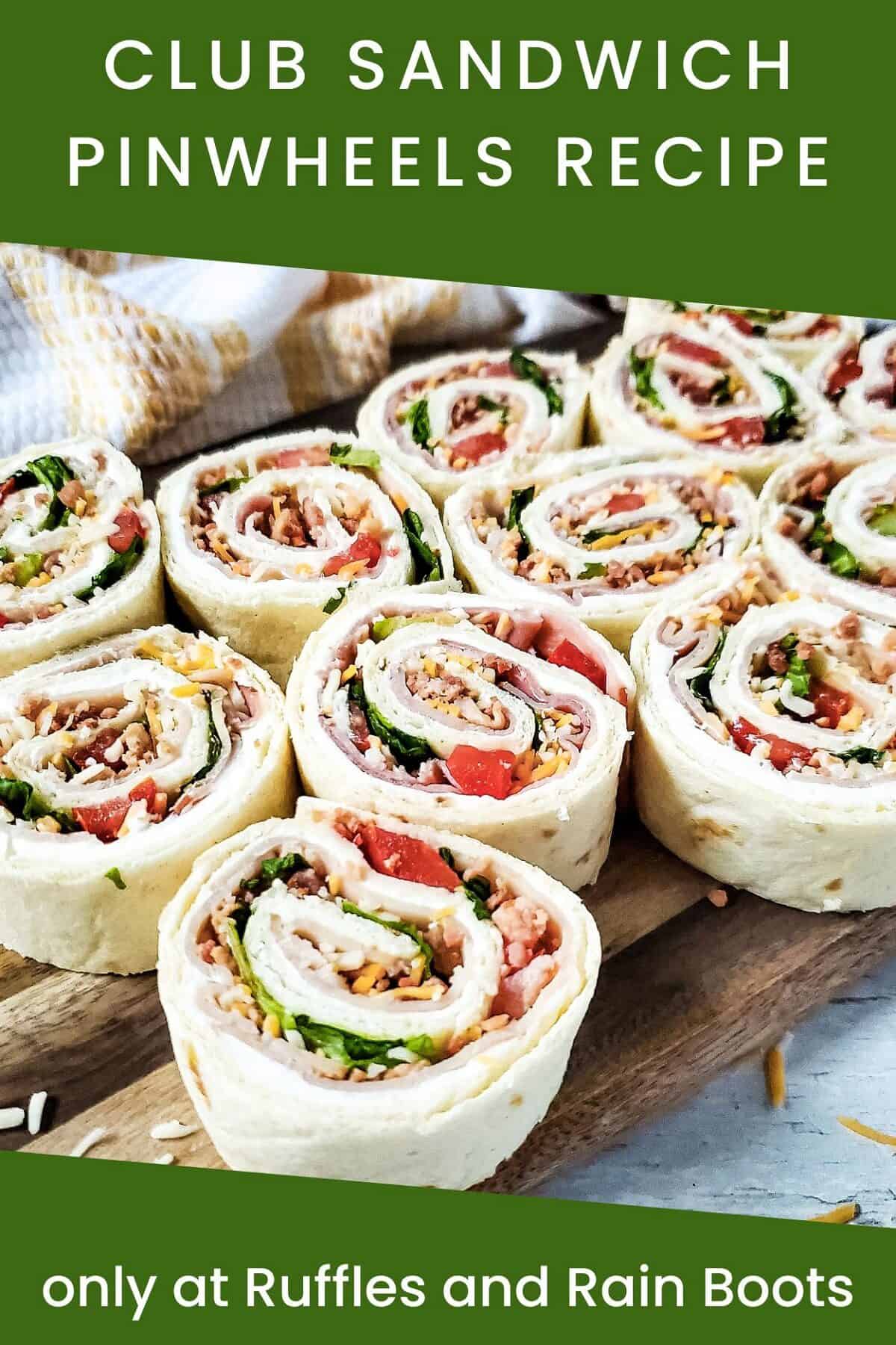 Front view of the rolled Club Sandwich Pinwheels Recipe on a wooden cutting board next to a beige and white towel on a marble surface.