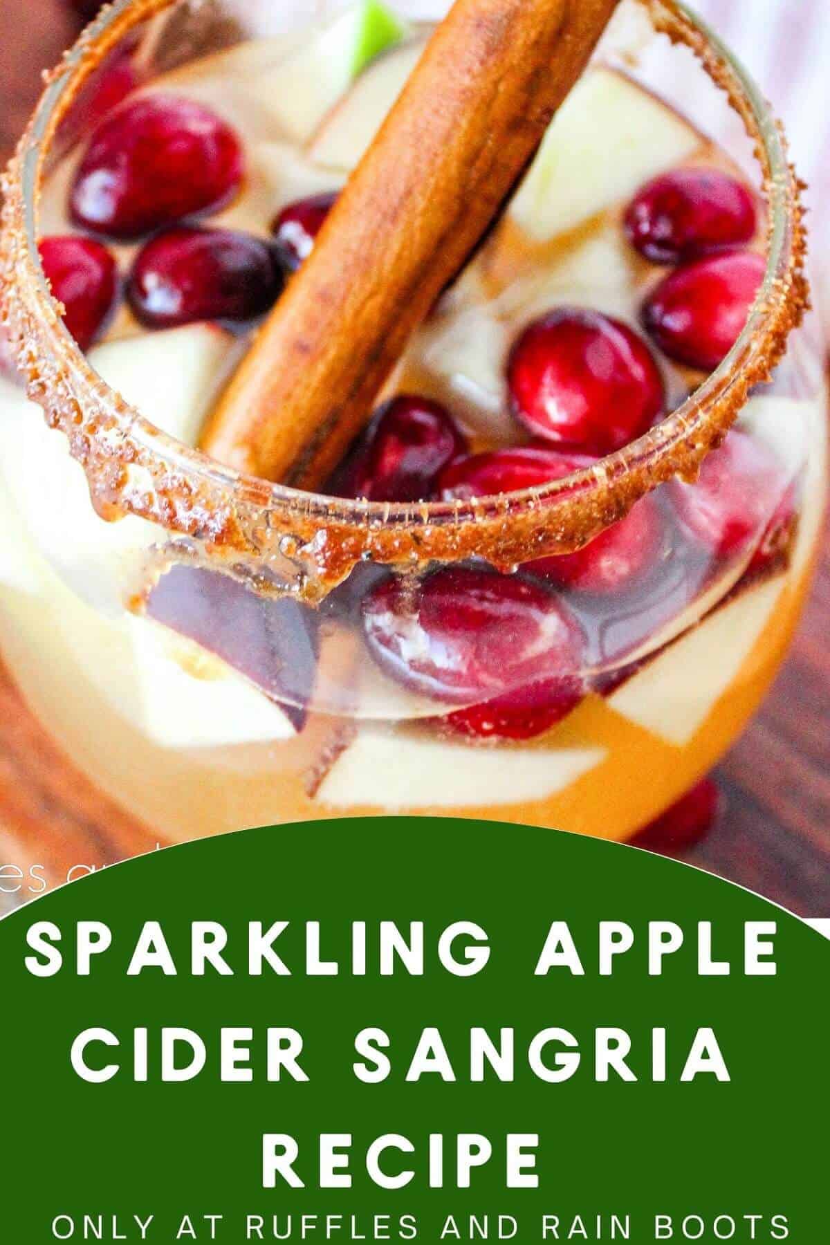 A image of a glass filled with Sparkling Apple Cider Sangria and garnished by a cinnamon stick, on a wooden board, on a white surface.