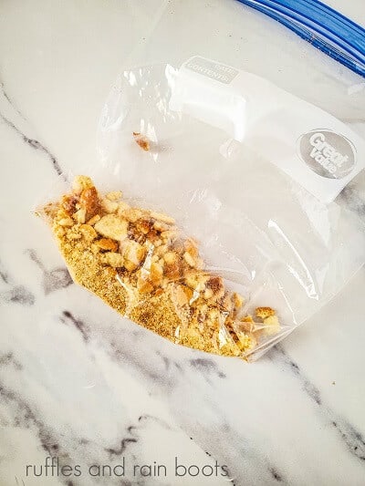 A clear Ziplock bag with crushed vanilla wafers on a white marble background.