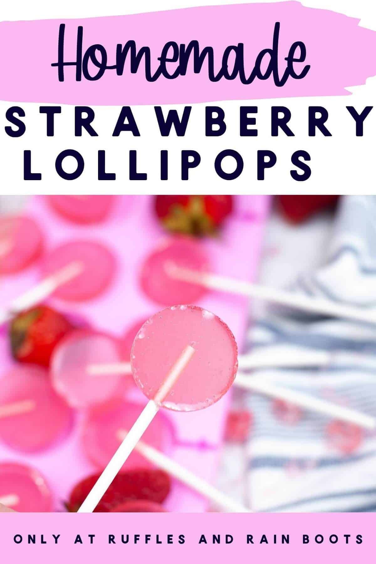 Close-up of a strawberry lollipop with a mold filled with more lollipops and fresh strawberries next to a blue and white towel.