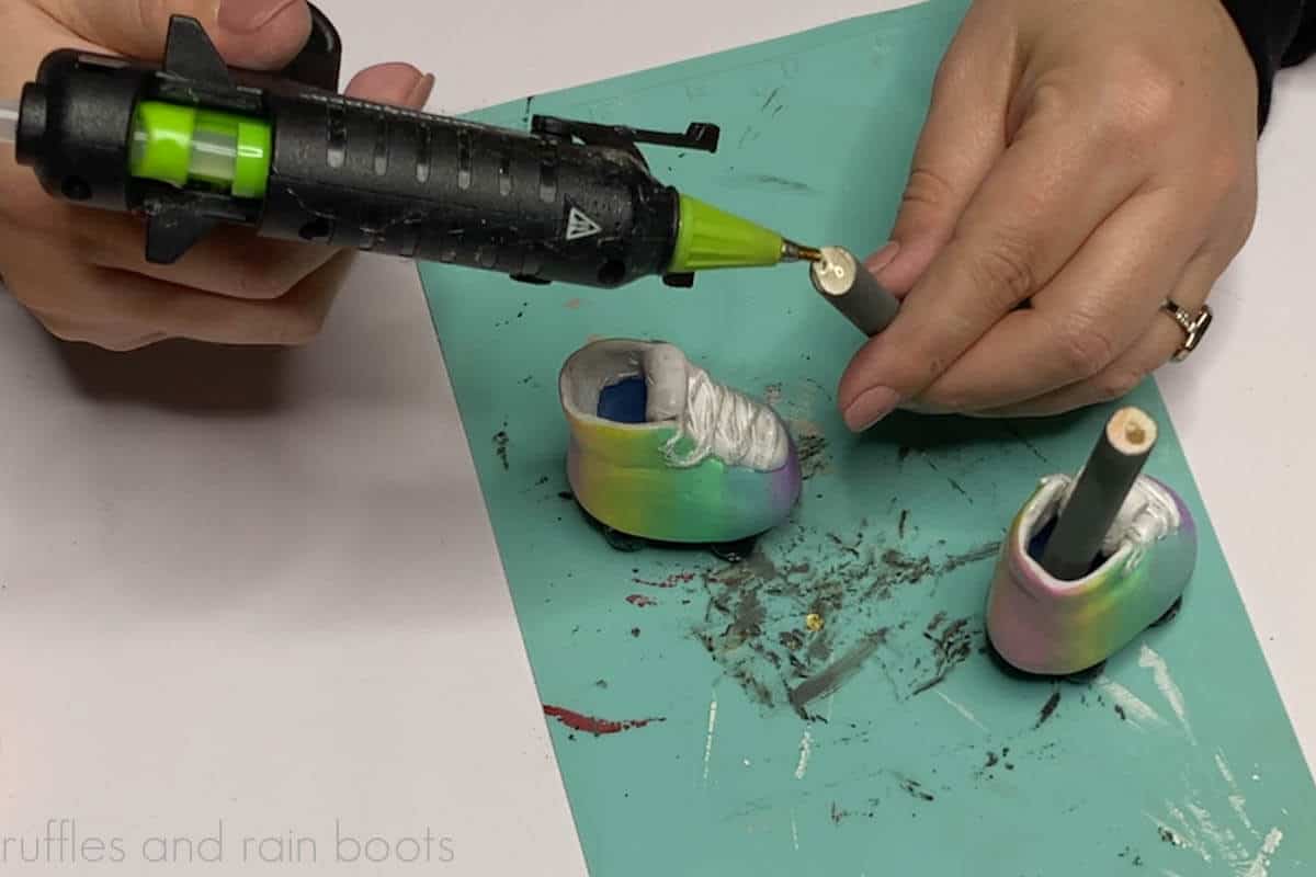Crafter using hot glue to secure wood sticks into the base of the roller skates.