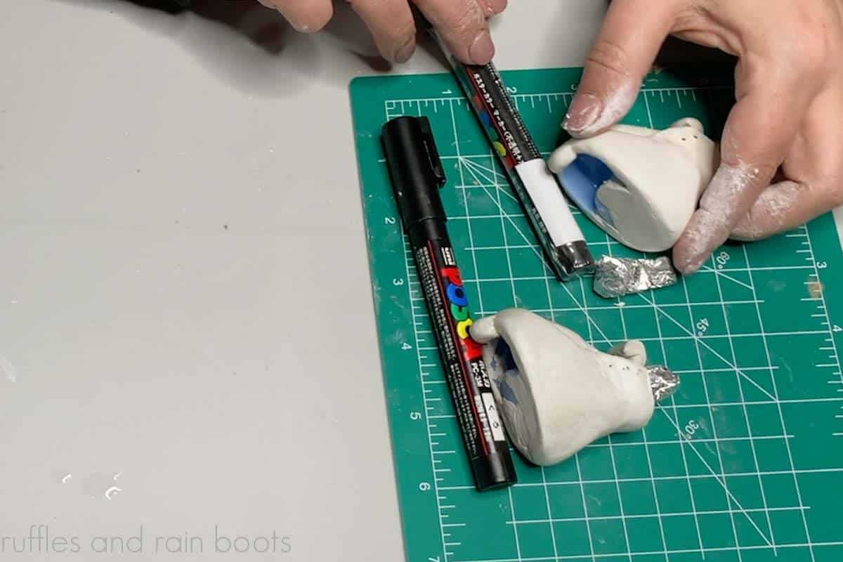Crafter using markers and foil to prop up air dry clay gnome boots.