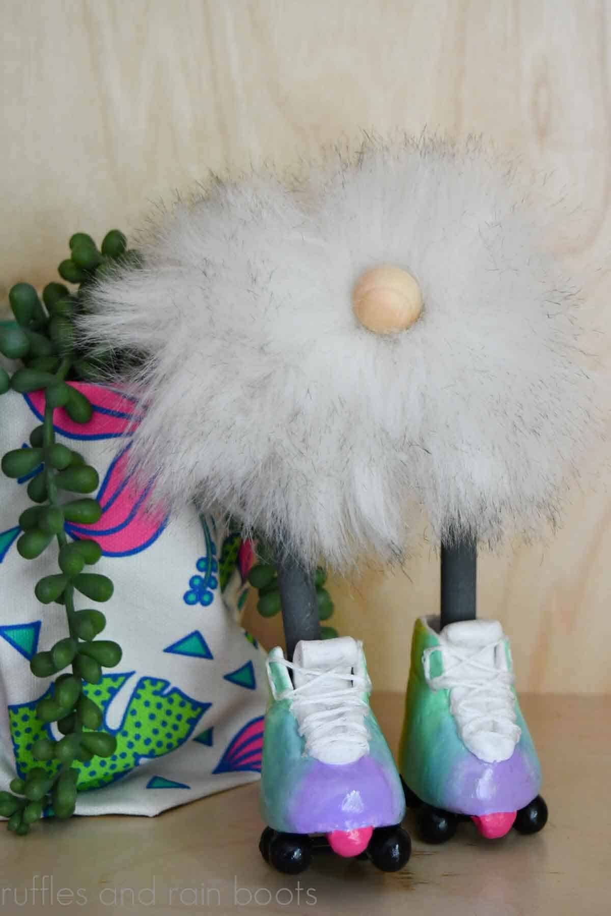 Vertical image close up of a white pompom gnome for summer made with roller skates on a wood background.