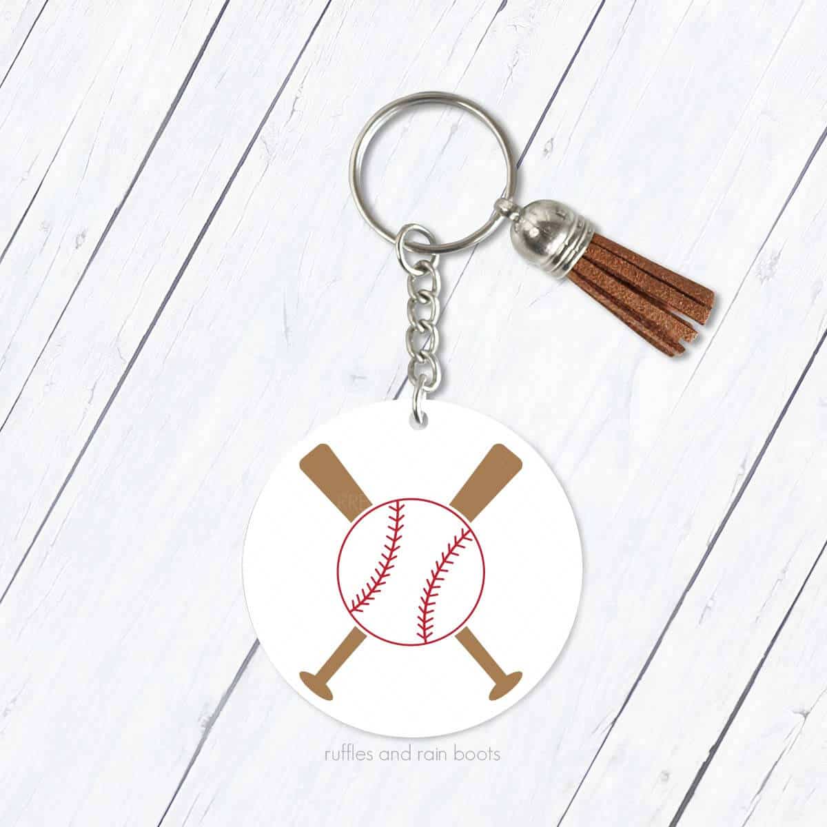 Square close up image of a white acrylic keychain with baseball and crossed bats SVG on wood background.