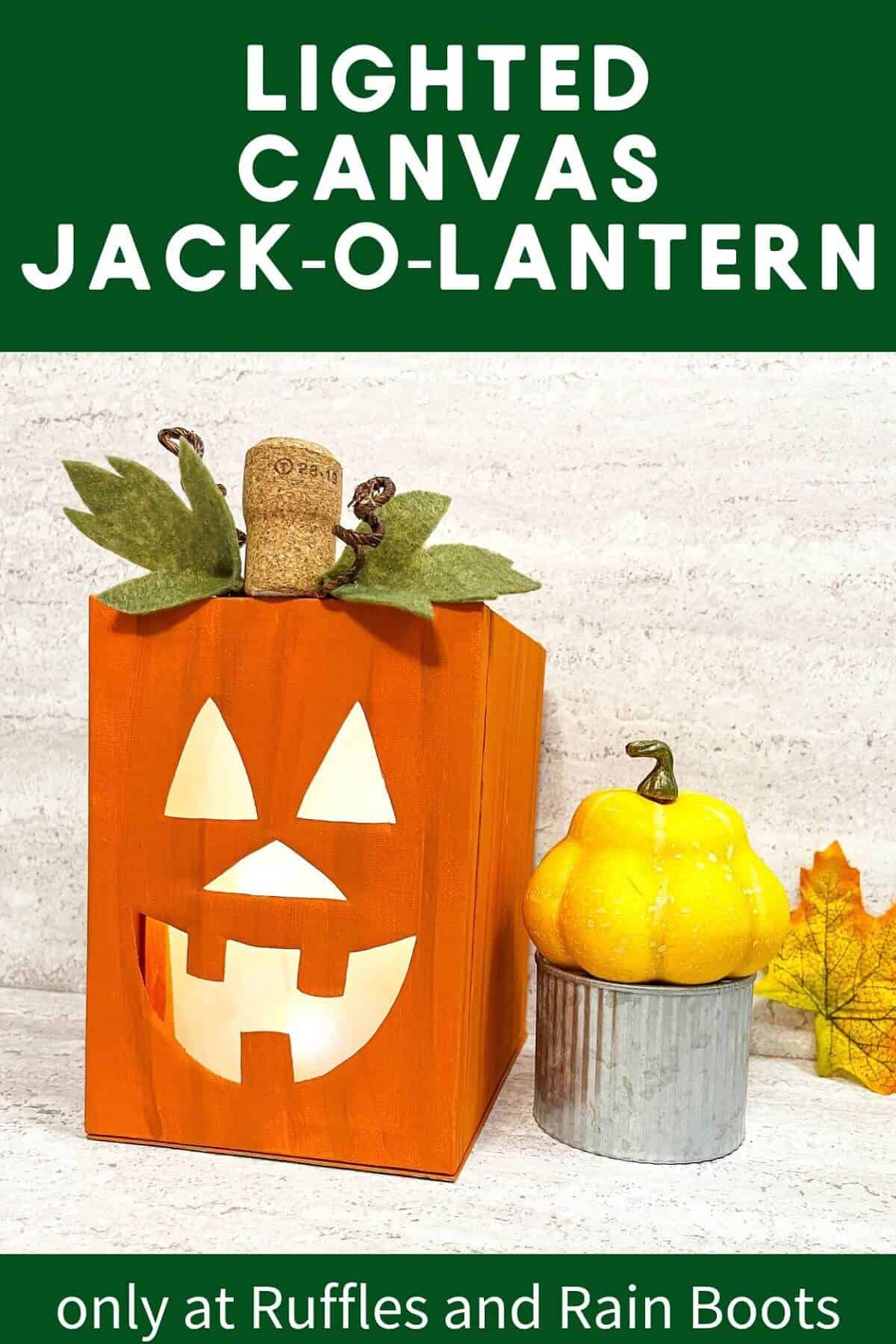 Vertical image of a completed lighted canvas Jack-O-Lantern craft next to a fall squash on a metal tin next to a fall leaf against a white and grey background.