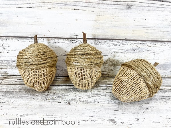 Three completed Dollar Tree Acorns against a white weathered wood background.