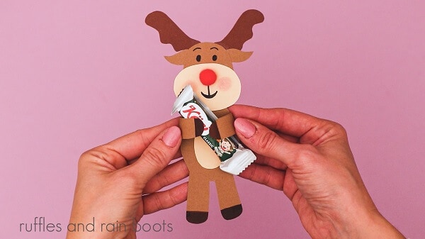 Crafter holding a reindeer candy holder with a piece of candy against a purple background.