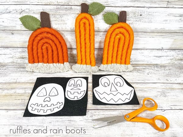 Three rope pumpkins with the Jack-O-Lantern template on craft felt next to a pair of scissors against a white weathered wood background.