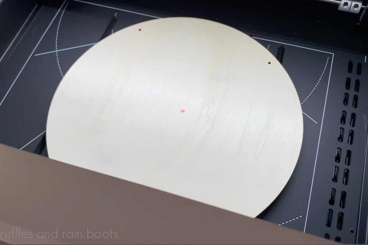 Image of a wood round on triangle prisms on the baseplate of the xTool M1 laser.