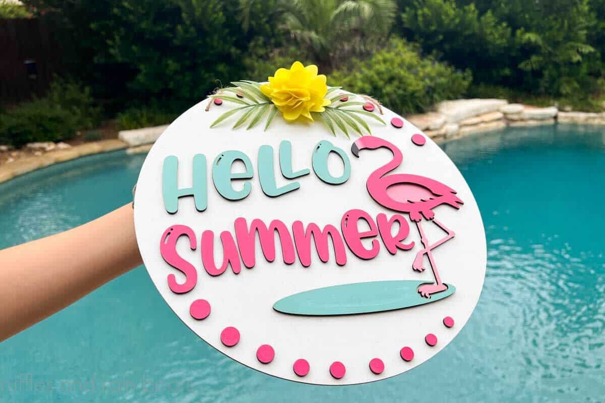 Horizontal image of woman holding a hello summer door sign with a flamingo made on the xTool M1 laser.
