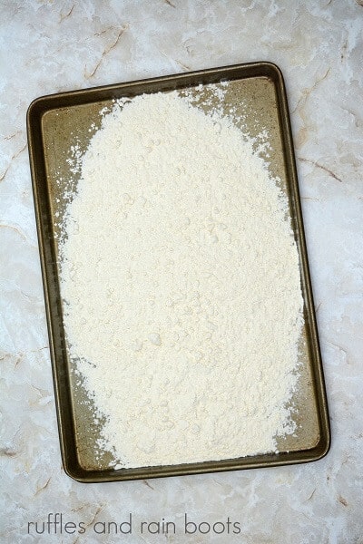 A large baking pan filled with flour against a marble background.