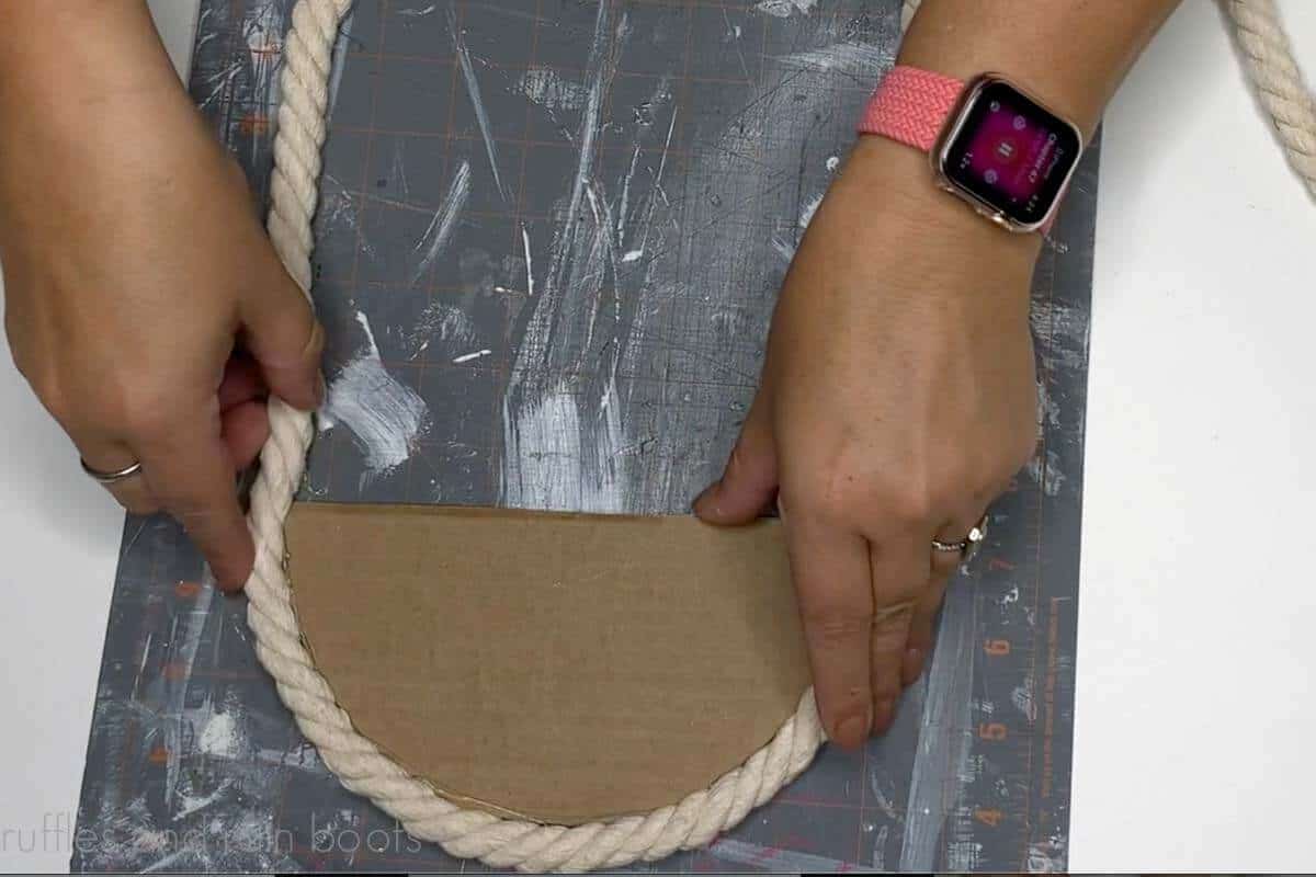 Crafter gluing a white cotton rope to the outside edge of a cardboard semi circle.