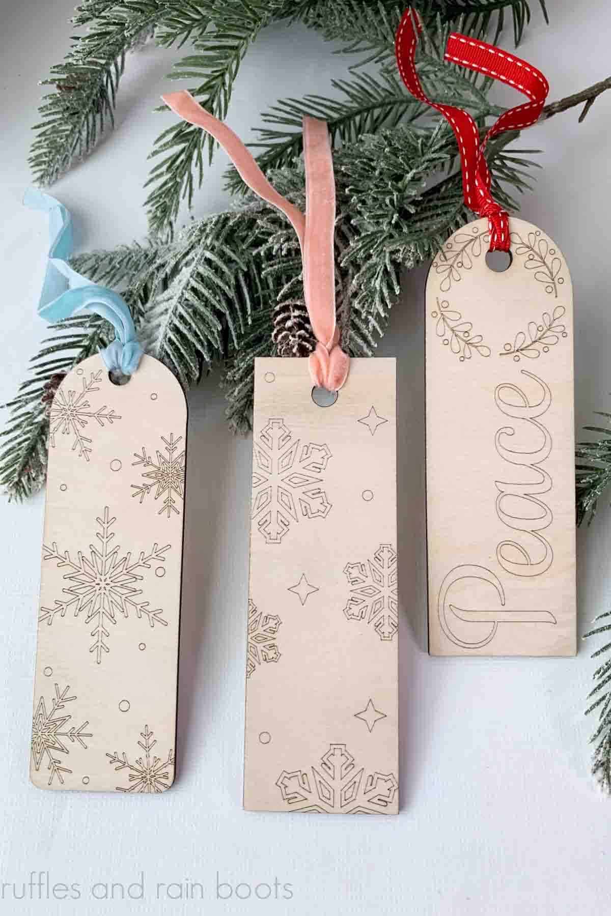 Vertical image of three wood bookmarks created for a painting set with ribbons on a Christmas background.