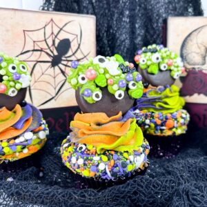 Three Hocus Pocus cauldron cupcakes on black netting against Halloween themed decor