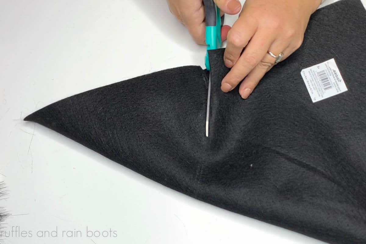 Close up image of a crafter cutting a cone from black felt to make a witch hat.