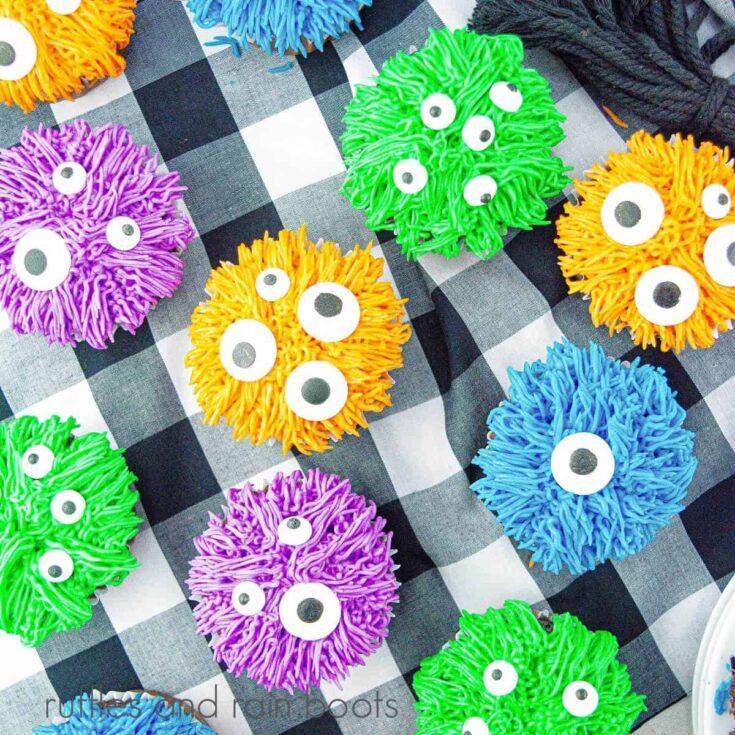 An overhead image of purple, blue, green and orange monster cupcakes on a buffalo plaid napkin.