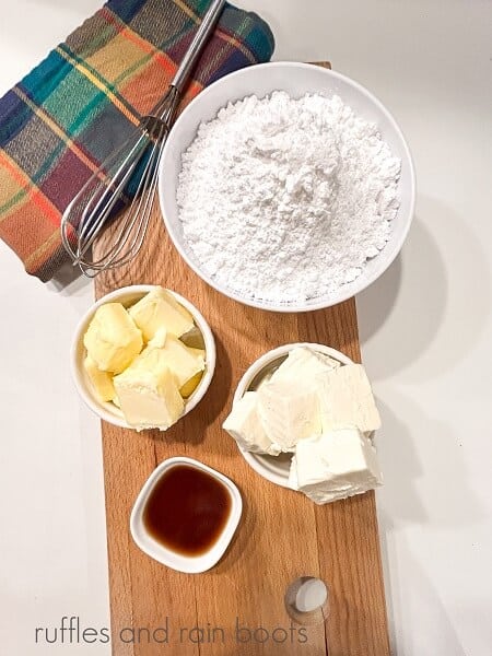 The supplies for the easy cream cheese frosting on a wooden cutting board against a white wooden backdrop.