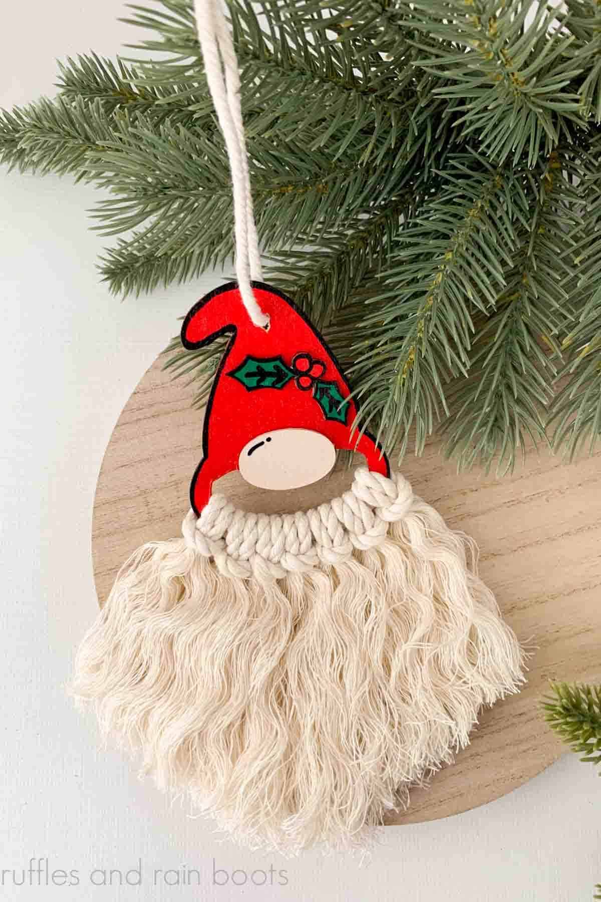 DIY gnome ornament made with laser or Cricut and a macrame beard on pine branches and white background.