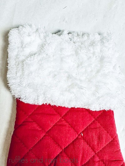 A red oven mitt with a white duster cloth glued to it against a white background.