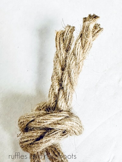 A piece of nautical rope tied into a knot against a white background.