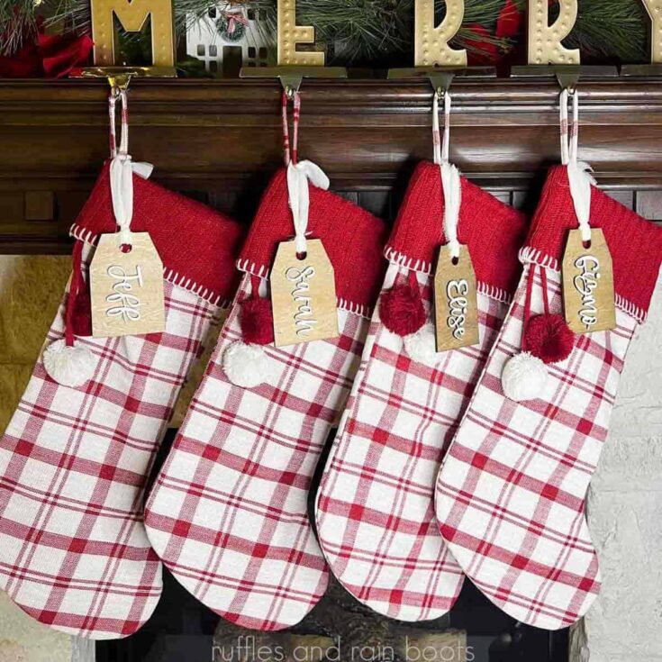 Square close up image of four red plaid stockings hung on a mantel with wooden stocking name tags.
