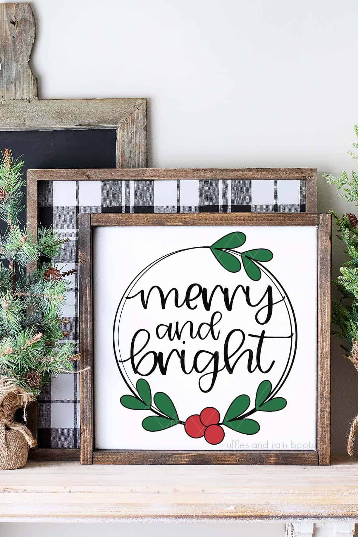 Vertical image of a DIY Christmas sign made with a merry and bright design with holly and a wreath on a kitchen shelf.