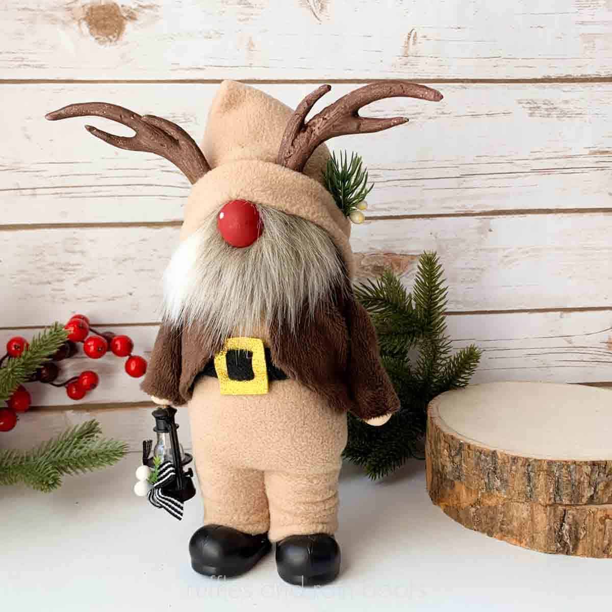 Close up square image of a reindeer gnome with foam antlers, hands, boots, pants, and a jacket.