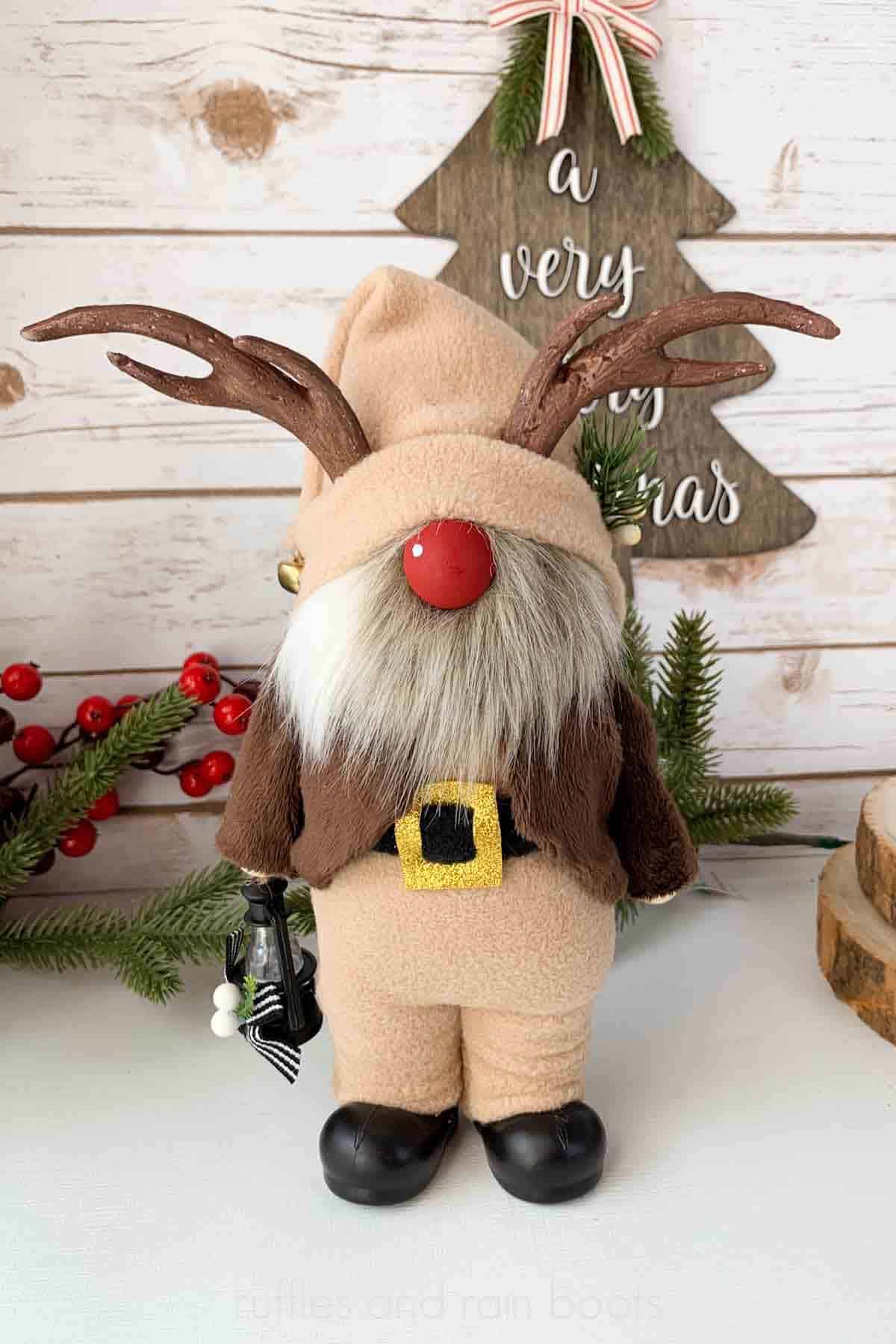 Vertical image of a reindeer gnome in light brown and dark brown wearing boots.