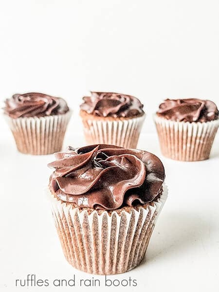 A German chocolate cupcake topped with a chocolate ganache against a white surface.