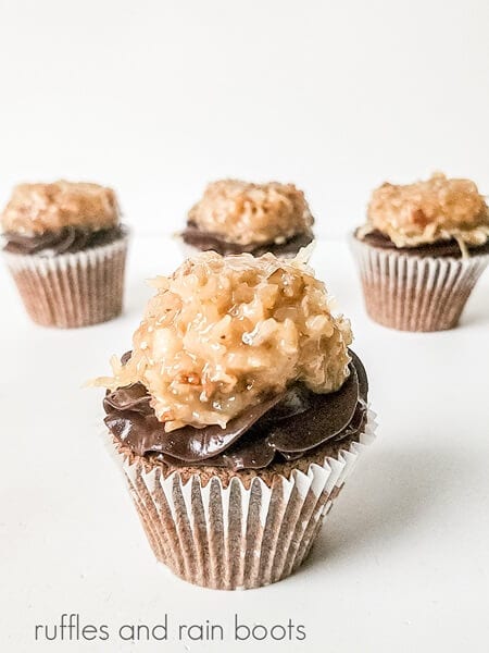 Coconut and pecan mixture added to the top of a frosted German chocolate cupcake against a white surface.