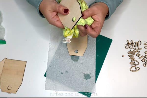 Crafter using a microfiber cloth to remove soot from laser cut wood.