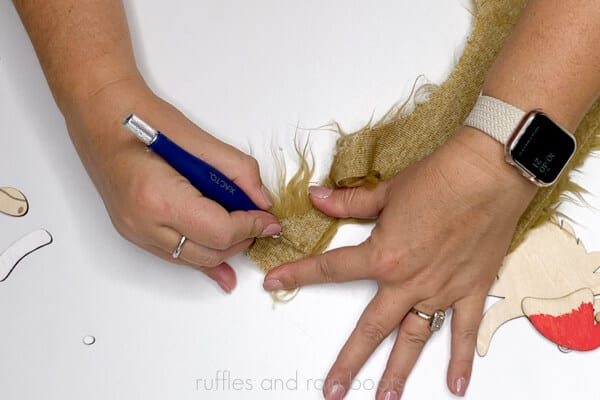 Crafter using an X-Acto knife to cut a small piece of faux fur for the Scottish highland cow ornament.