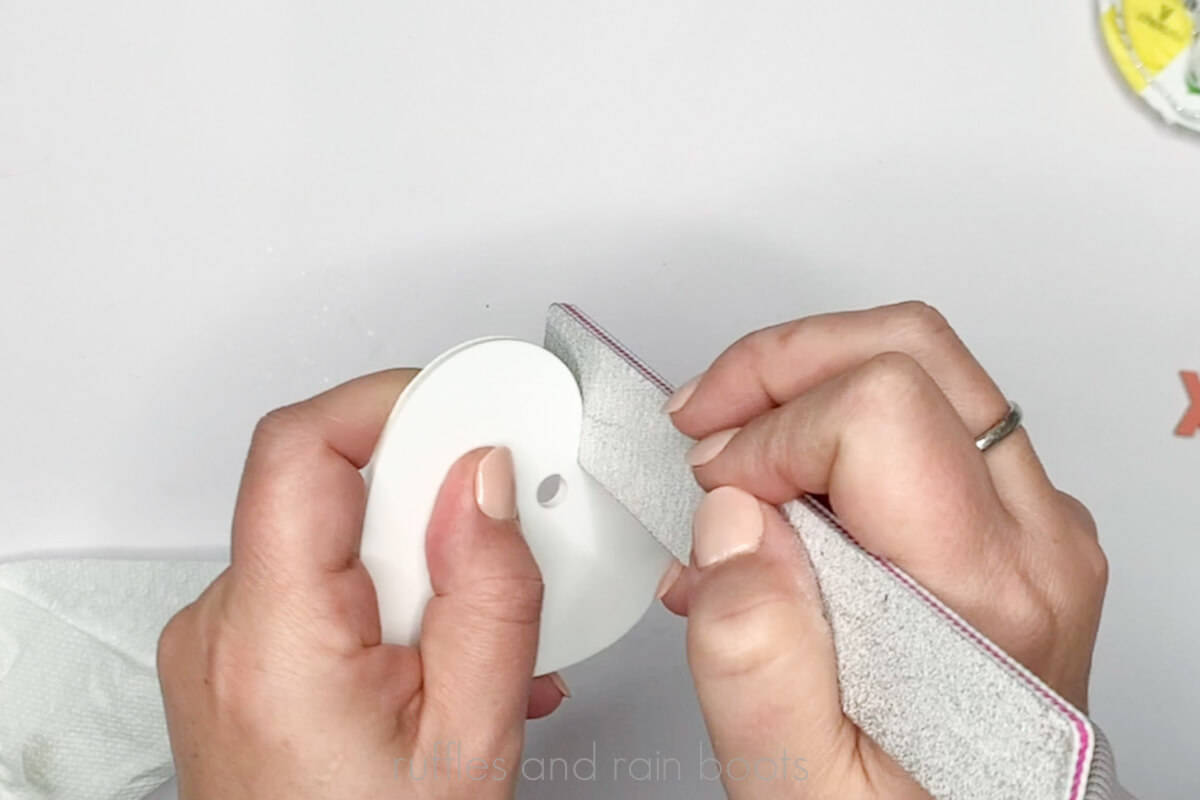Crafter using a nail file to clean up the edge of a white acrylic heart.