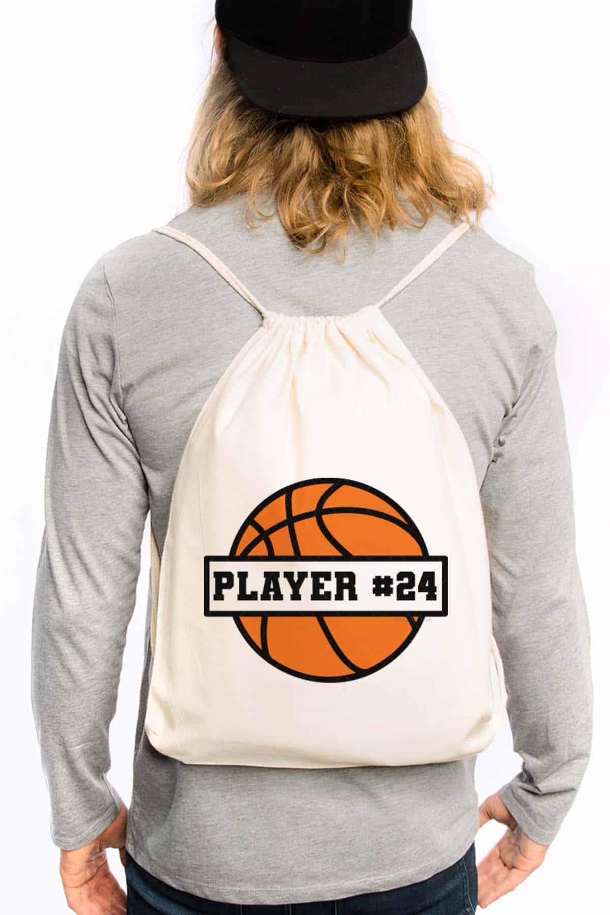 Vertical image of a man in a light gray long sleeve shirt with a drawstring backpack with a basketball in orange and black.