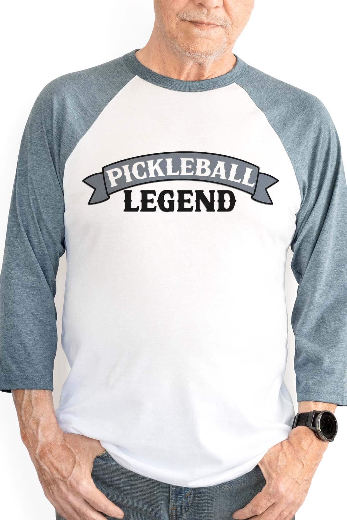 Vertical image of an older man in a raglan shirt with pickleball legend in black and blue vinyl.