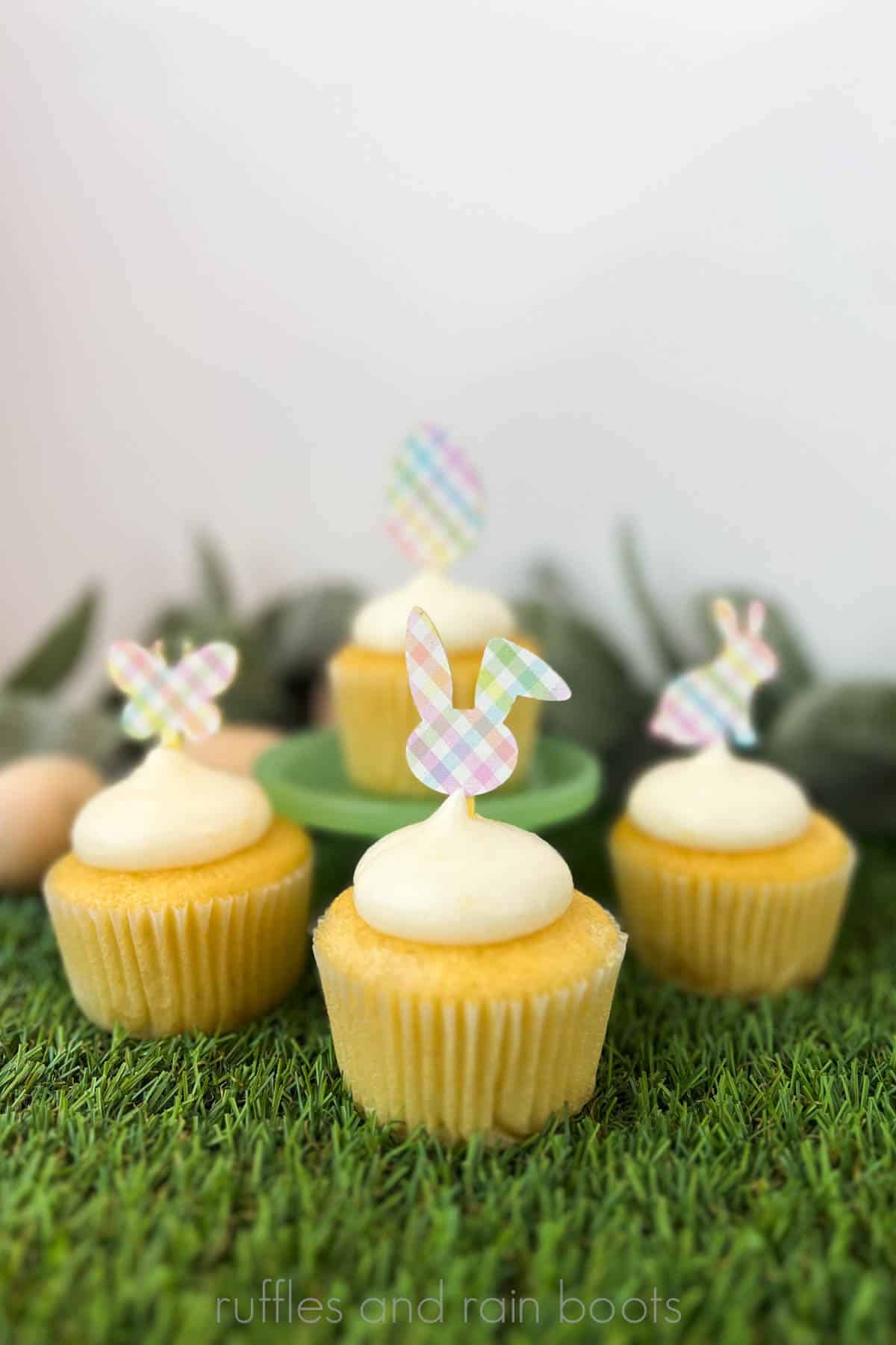 Vertical image of Easter cupcake toppers in laser safe plaid on yellow acrylic pressed into lemon cupcakes on a faux green grass background.