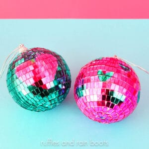 Square close up image of two pink and teal disco balls painted with hearts on a blue and pink background.