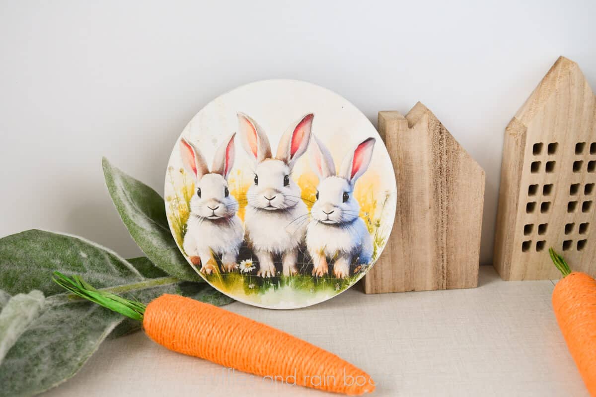 Horizontal image of three bunnies in a field printed onto mulberry paper and decoupaged onto a dollar store plaque.