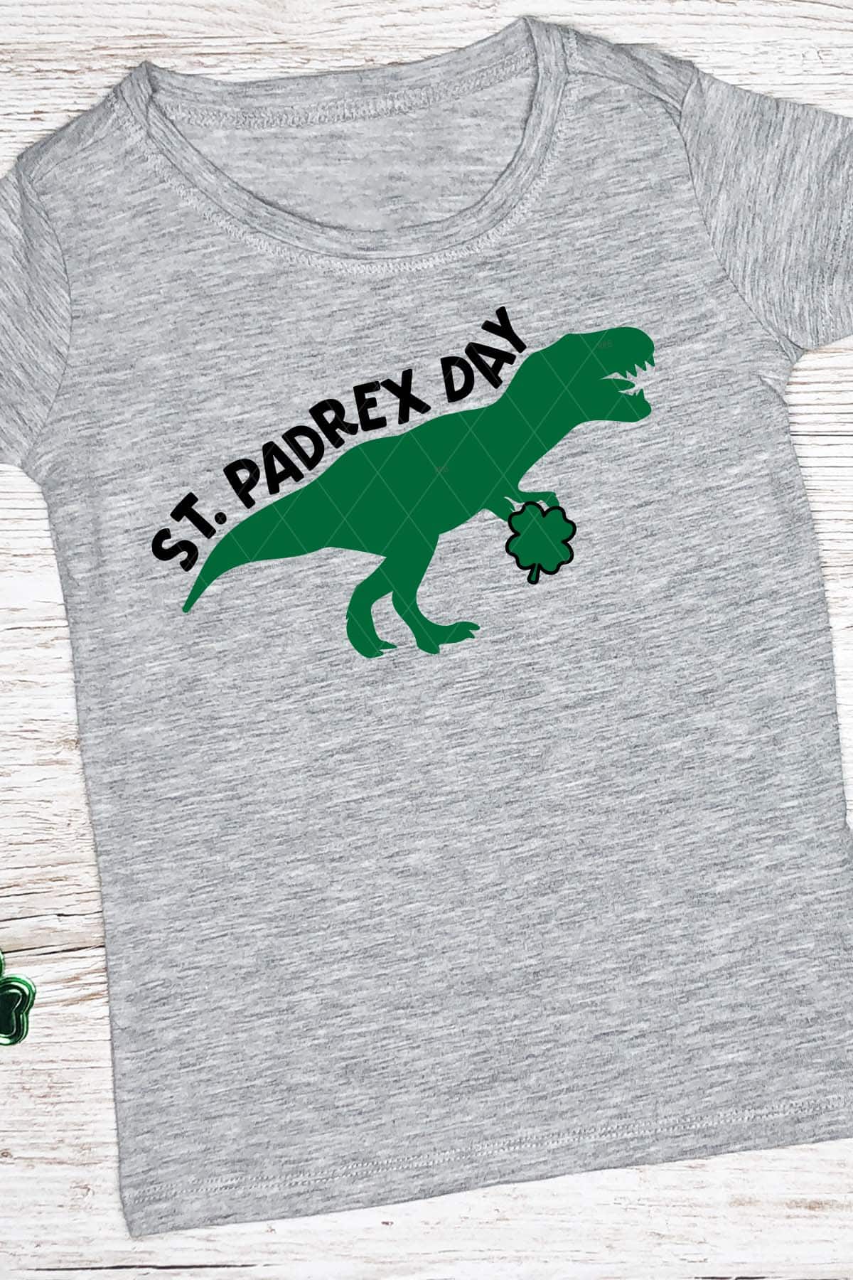 T-Rex holding a clover in black and green vinyl on gray t-shirt which reads st padrex day.