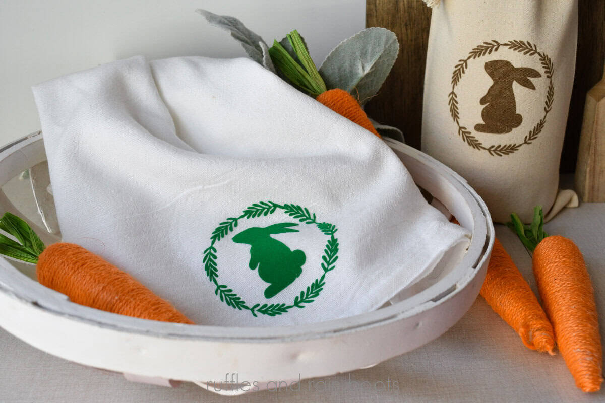 Horizontal image of a flock heat transfer vinyl bunny and wreath on a flour sack towel and an engraved wine bag with an Easter theme, made with the xTool M1 Ultra.