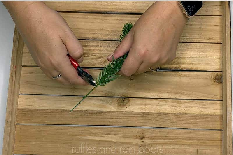 Crafter using wire cutters to cut down pine sprigs.