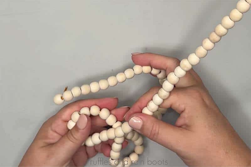 Crafter bending wood bead covered wire to form butterfly wings.