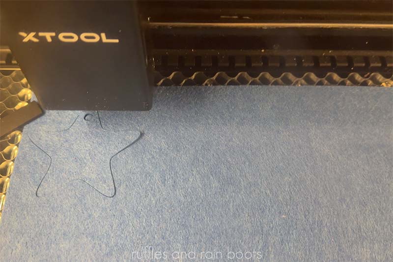 xTool P2 laser cutting 3mm blue felt into a star shape for a felt garland.