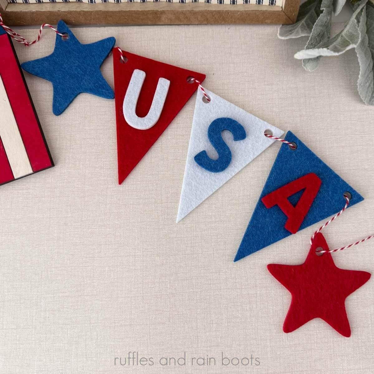 Close up square image of a July 4th Independence Day garland made of red, white, and blue thick felt.