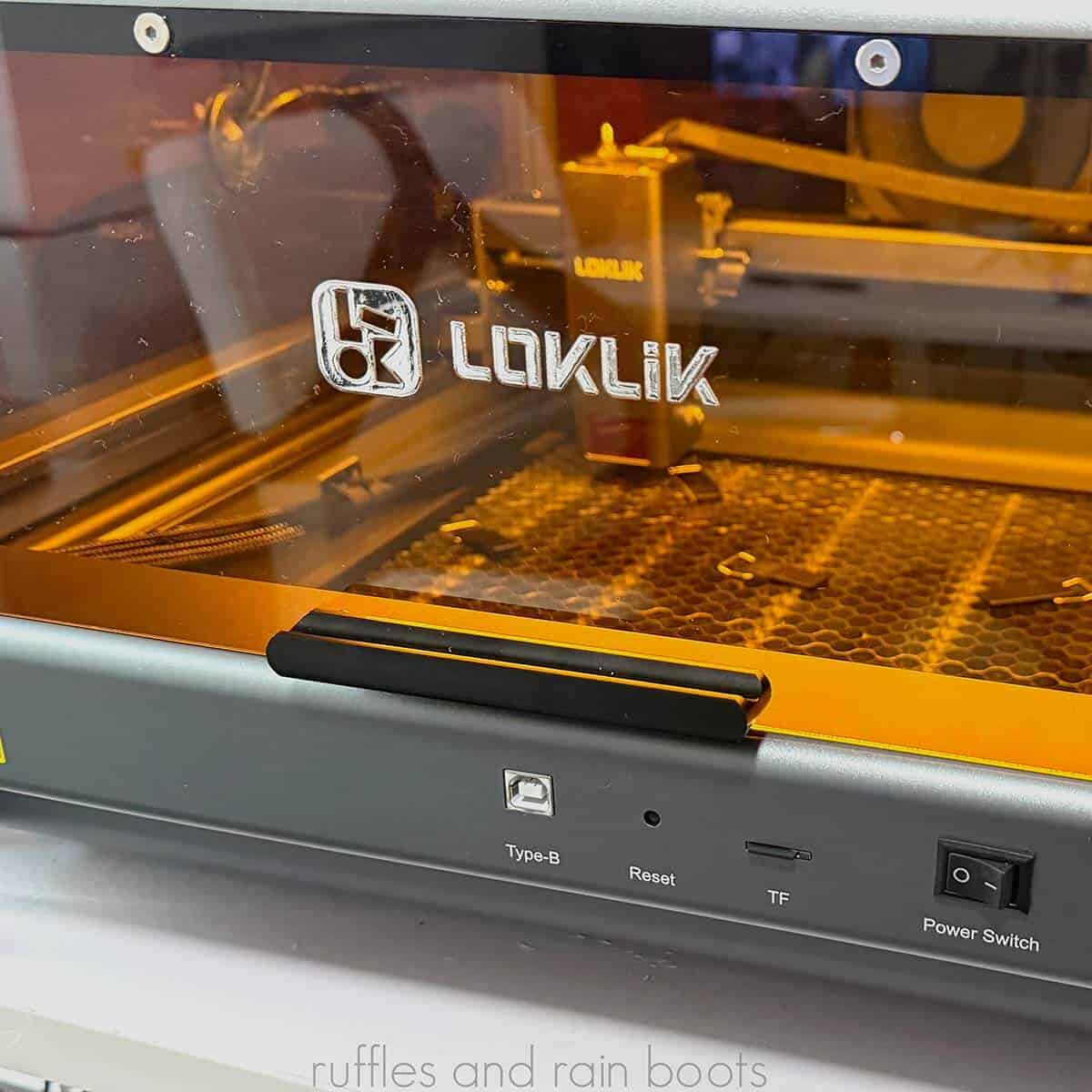 Square close up image of the LOKLiK iEngrave laser Cover edition lit up on a white table.
