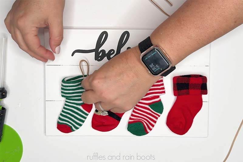 Image of a crafter gluing looped cords into baby socks to create stocking hangers.