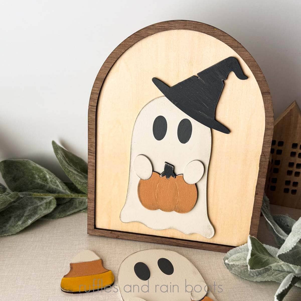 Square close up image of a Halloween ghost in a witch hat holding a pumpkin.